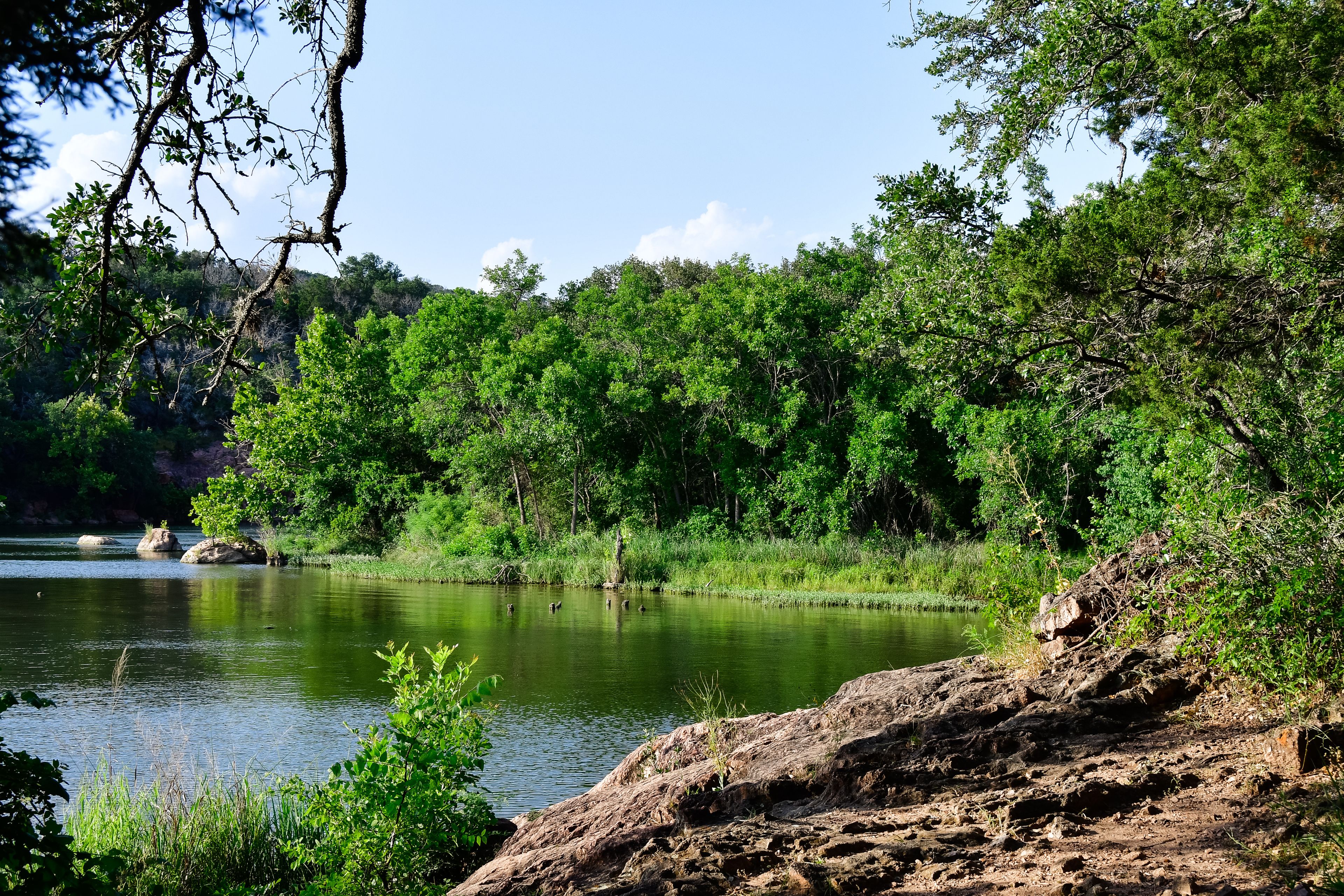 A serene lake surrounded by dense green forest and rocky terrain.