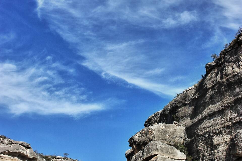 Un penya-segat rocos amb vegetació escassa sota un cel blau clar.