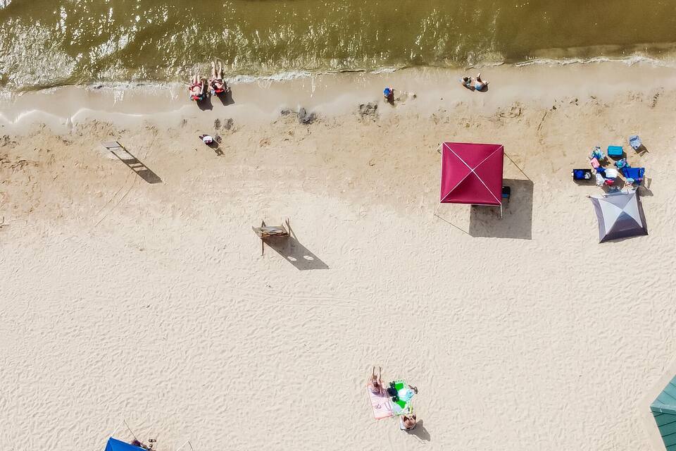 An aerial view of a beach with people, umbrellas, and beach chairs.