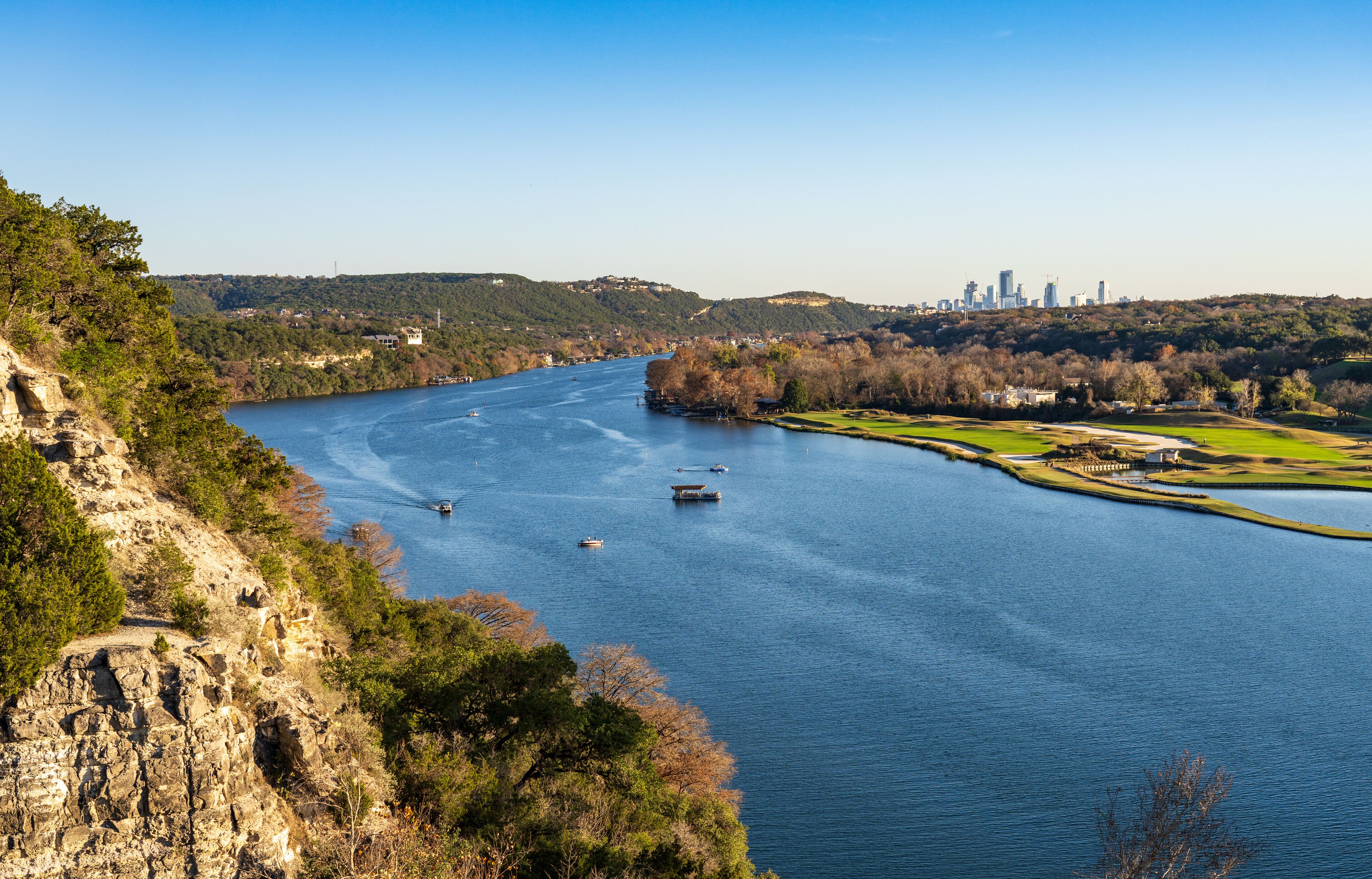 Golf course lines the Colorado river with downtown Austin Texas in distance from Pennybacker bridge overlook