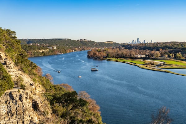 Golf course lines the Colorado river with downtown Austin Texas in distance from Pennybacker bridge overlook