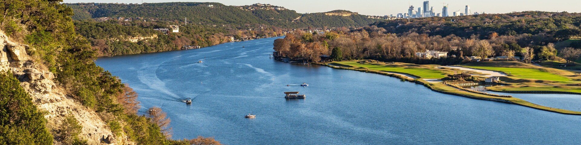 Golf course lines the Colorado river with downtown Austin Texas in distance from Pennybacker bridge overlook