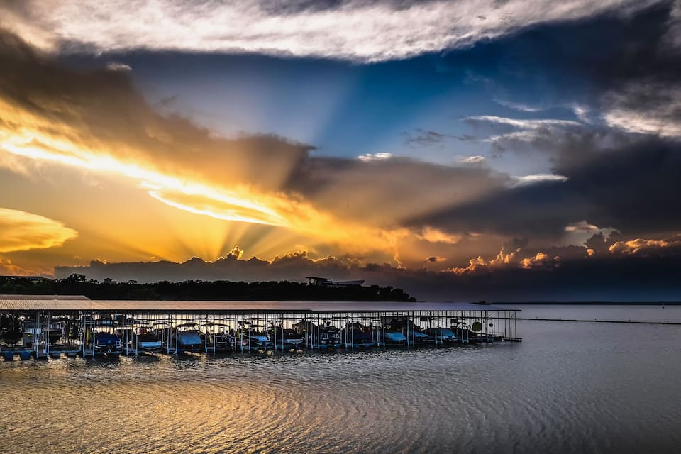 A pier extending into calm waters with a sunset sky.