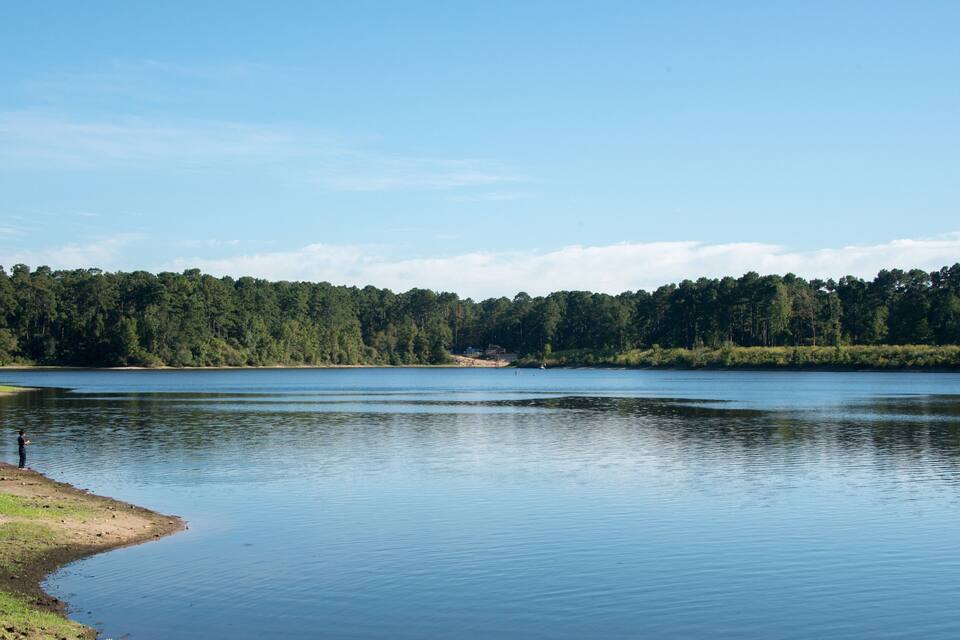 A calm lake with a forested shoreline and a few people fishing.