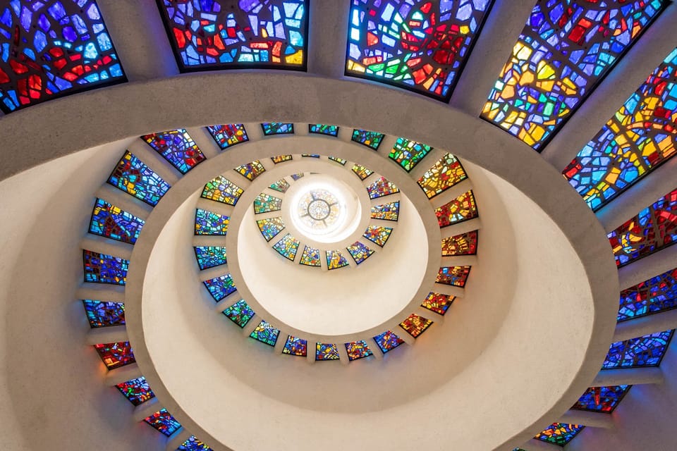 Uma escadaria em espiral com janelas de vitrais.