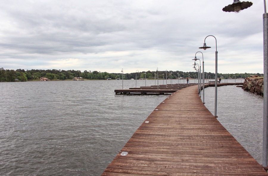 Un muelle de madera que se extiende sobre el agua, con una hilera de farolas a lo largo de su extensión.
