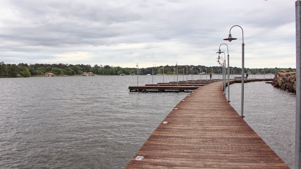 A wooden pier extending into a body of water, with a row of street lamps along its length.