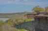 A concrete dam with a metal fence, a bridge, and a river.