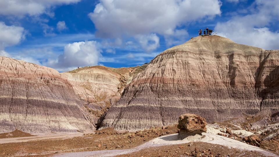 A rocky landscape with layered rock formations and a small group of people on a hill.
