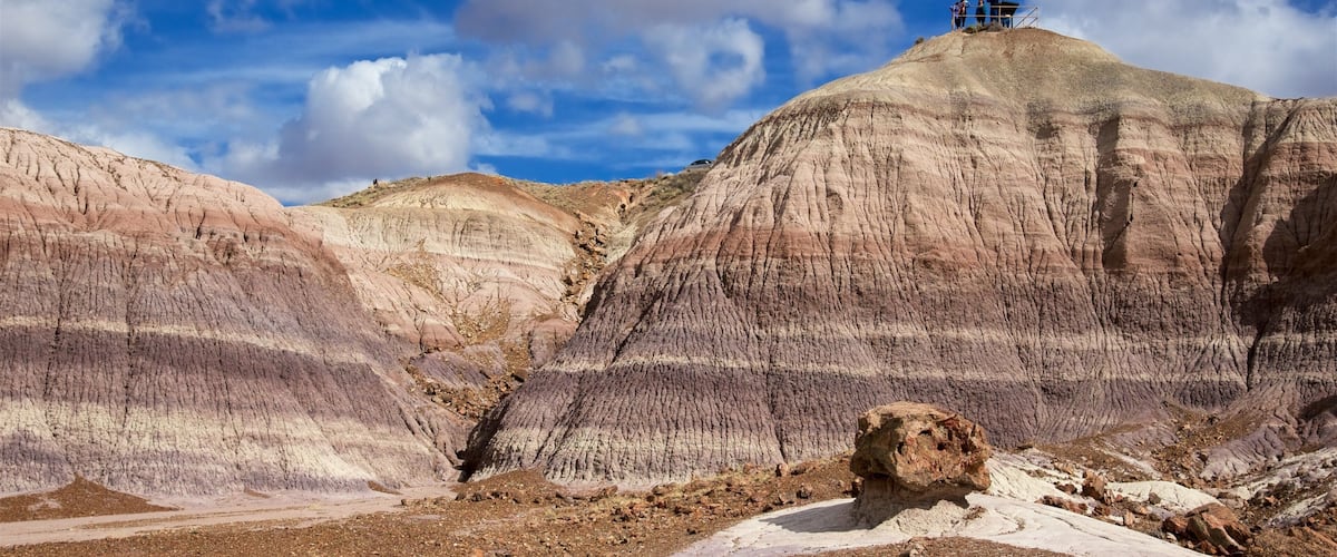 A rocky landscape with layered rock formations and a small group of people on a hill.