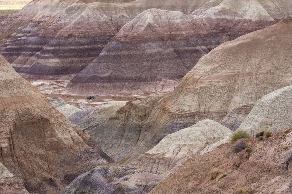 A rugged landscape with layered rock formations and a narrow valley.
