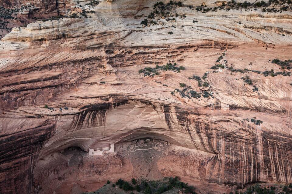 A large rock formation with visible stratification and a small cave-like structure at its base.