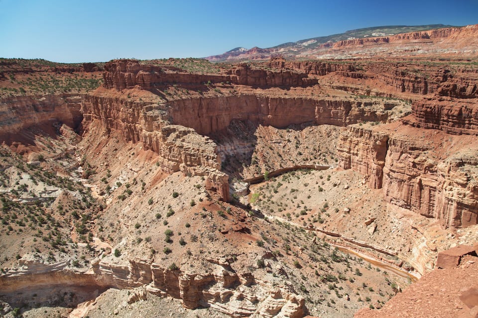 Eine Schlucht mit schichtartigen Felsformationen und vereinzelter Vegetation.