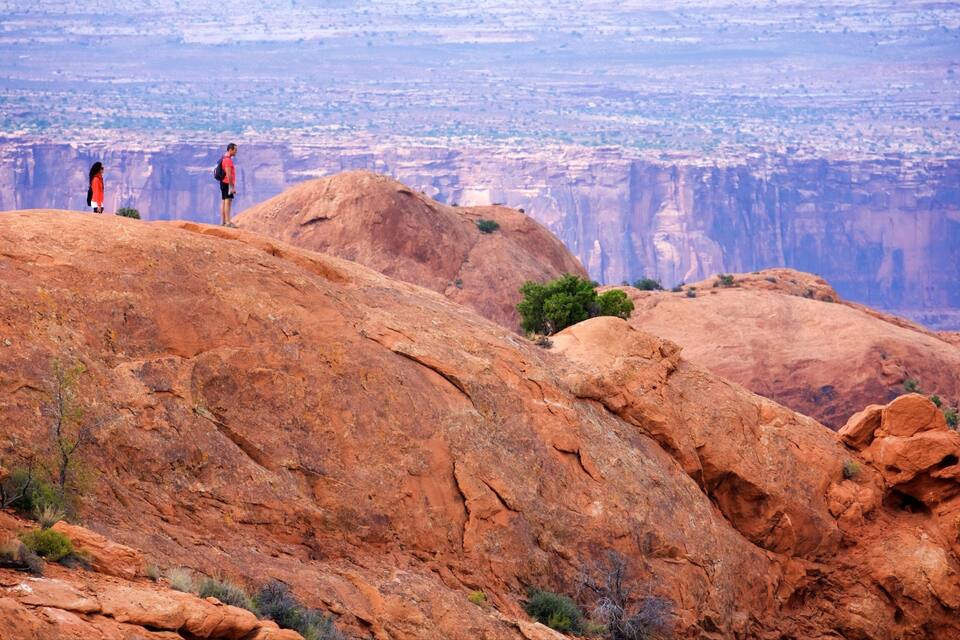 A canyon with red rock formations and two hikers.