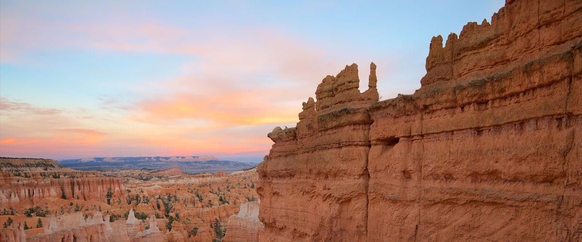 A canyon with layered rock formations and a sunset sky.