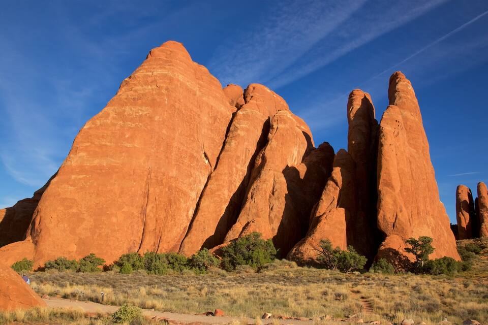 A landscape with large red rock formations and sparse vegetation under a clear blue sky.