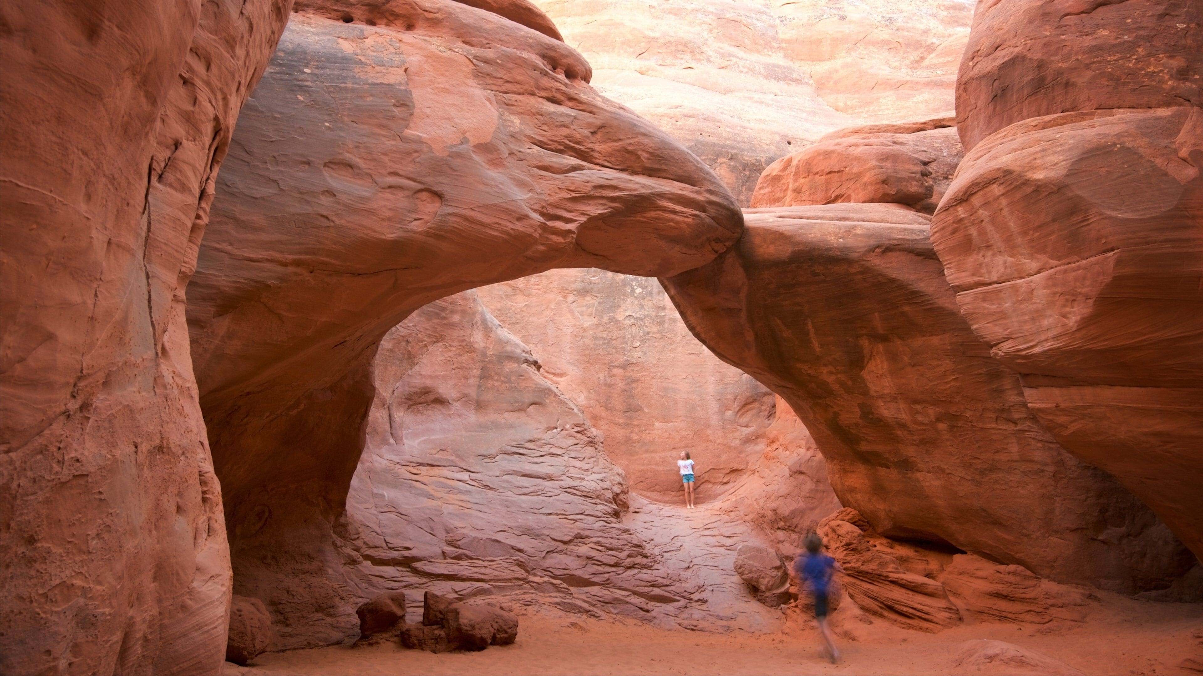 A person walking through a natural rock arch formation.