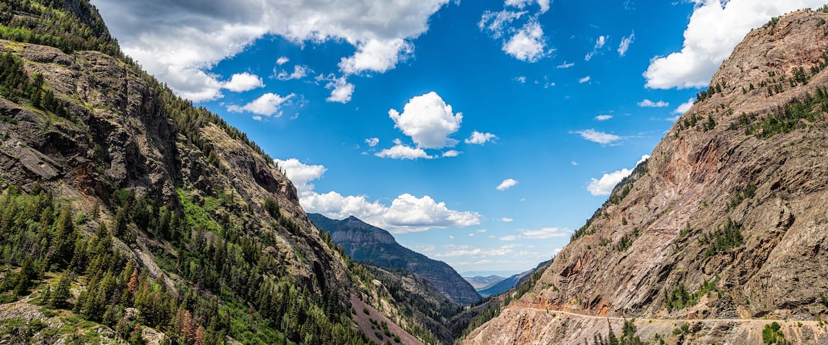 Framing of canyon valley on Million Dollar Highway in Ouray, Colorado with San Juan rocky mountains in summer and blue sky clouds