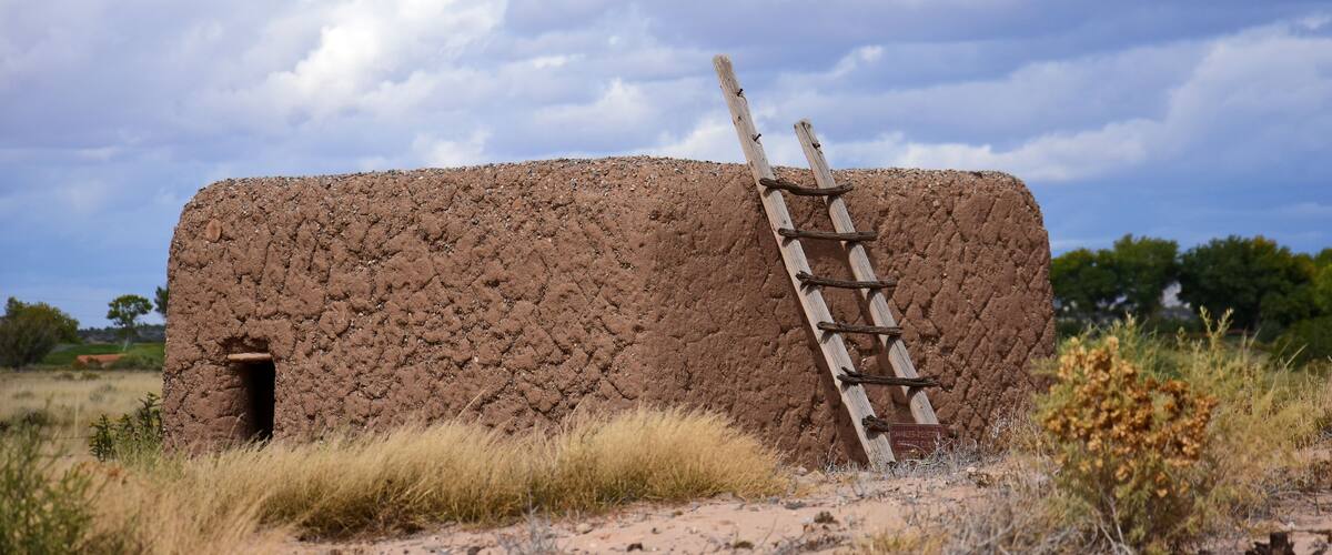 an adobe kiva and ladder on a stormy day at the coronado historic site in bernalilllo, new mexico