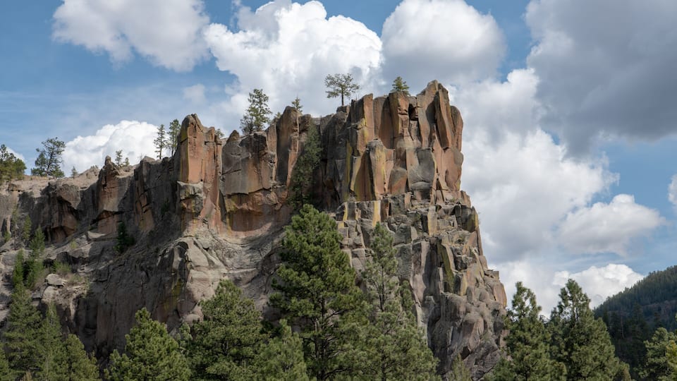 A rugged mountain with prominent rock formations and scattered trees.
