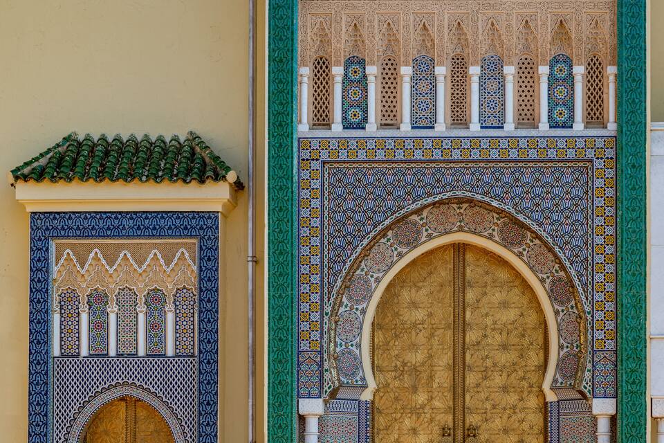 A detailed view of a traditional Moroccan gate with intricate tile work and a large wooden door.