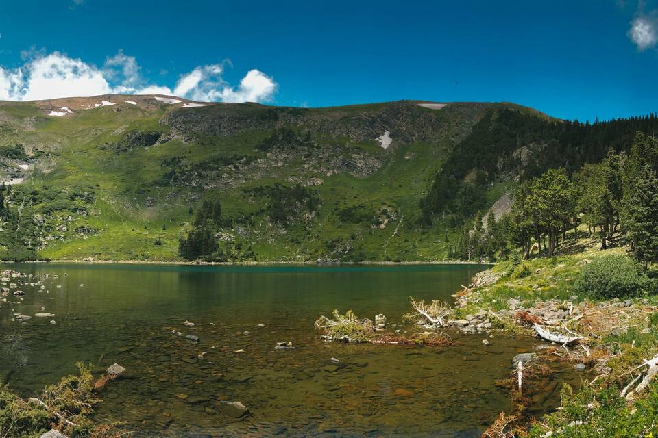 A mountain lake surrounded by dense forest and rocky terrain.