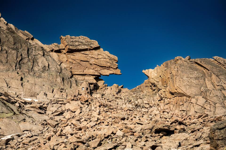 Un paisaje rocoso y accidentado con formaciones rocosas estratificadas y un cielo azul despejado.