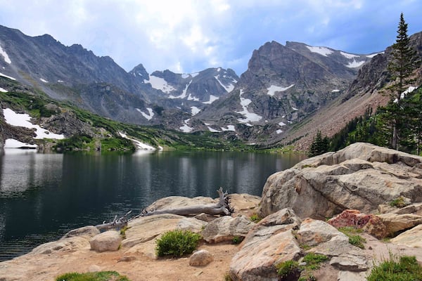 magnificent arapahoe, navajo, and shoshoni peaks with a mountain stream and snowfield on a sunny summer day along the lake isabele trail in the indian peaks wilderness area near nederland, colorado