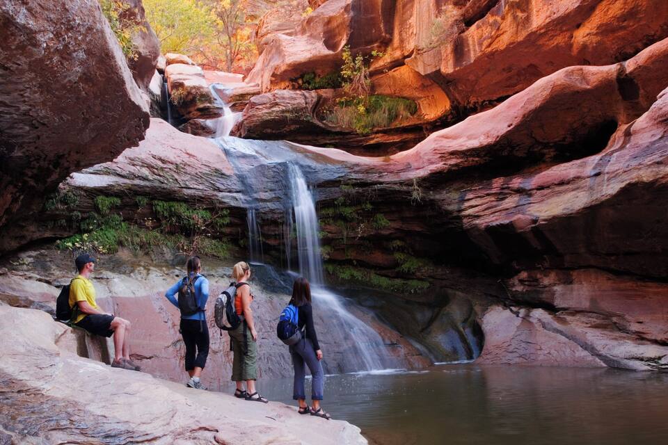 A waterfall cascading down a rocky cliff surrounded by hikers.