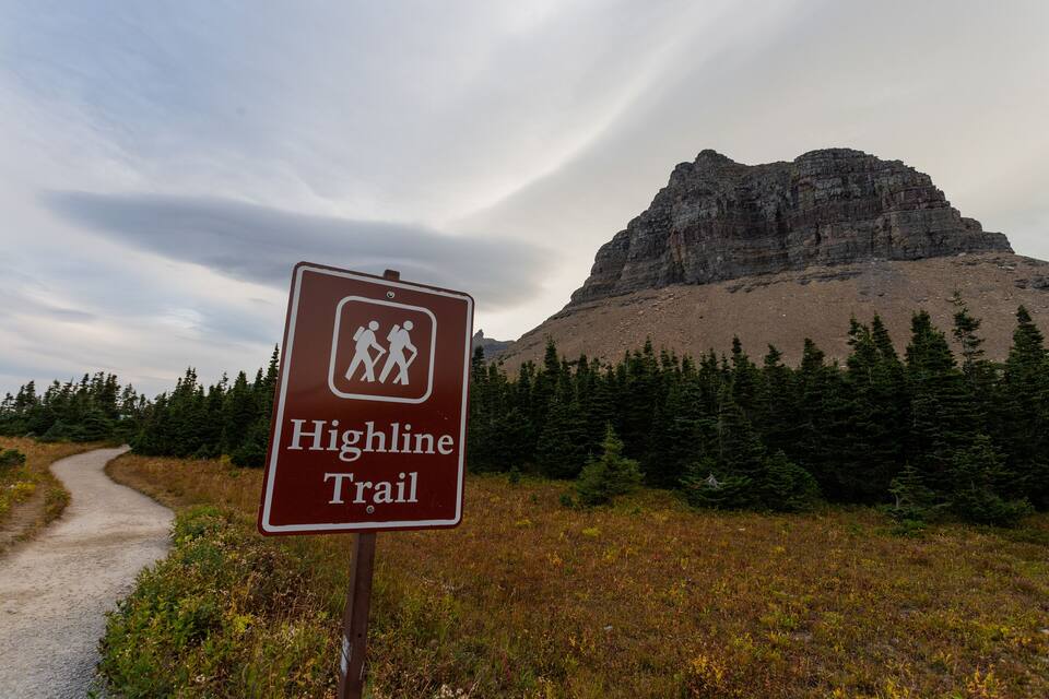 A sign for the Highline Trail with a mountainous backdrop.