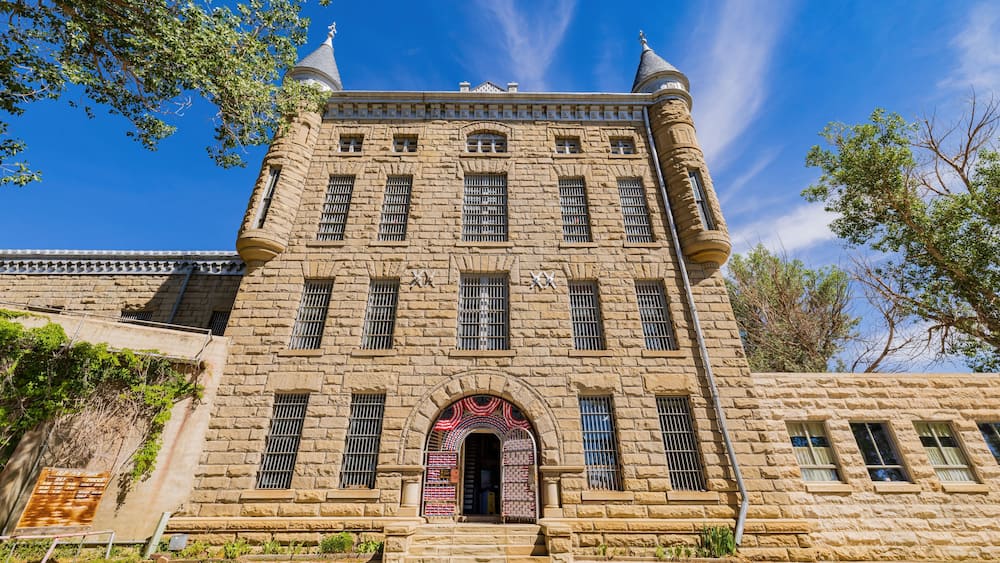 Ein historisches Steinhaus mit einem zentralen Rundbogenportal, zahlreichen Fenstern und dekorativen Elementen.