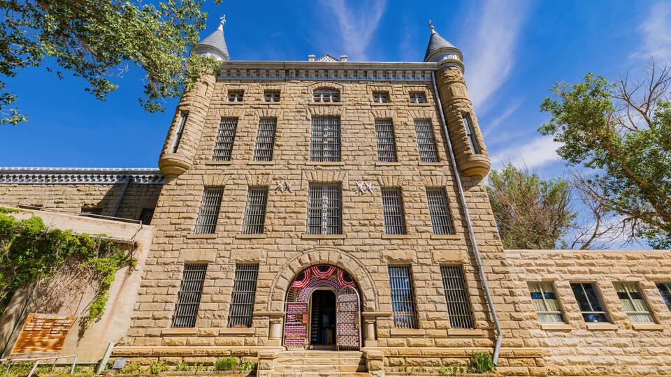 A historic stone building with a central arched entrance, multiple windows, and decorative elements.