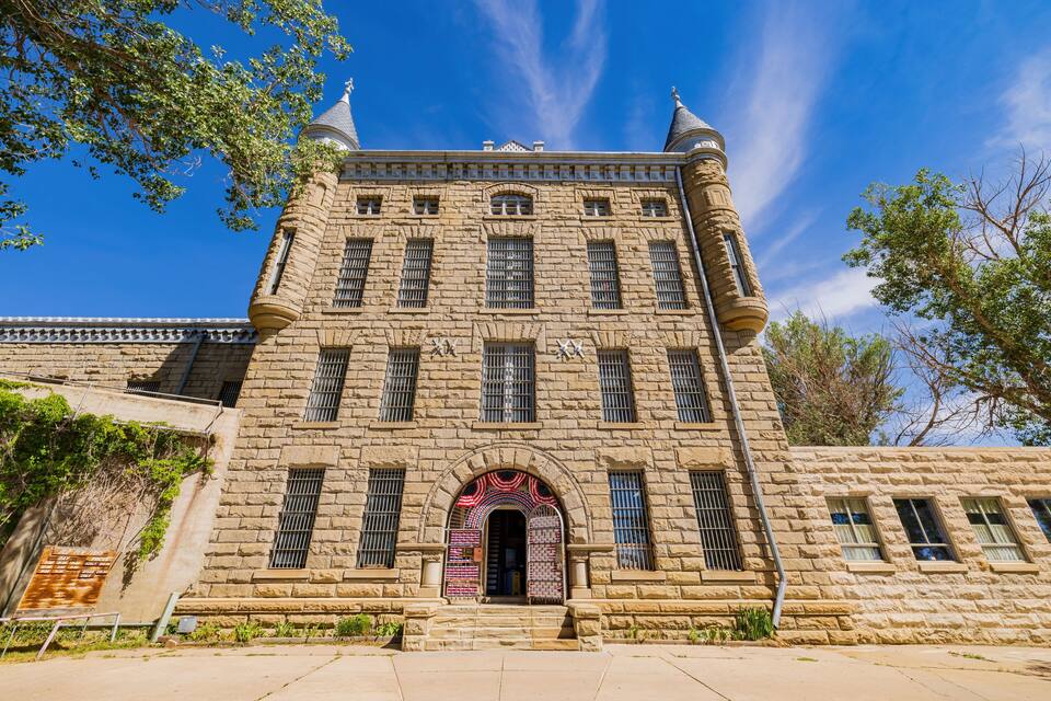 A historic stone building with a central arched entrance, multiple windows, and decorative elements.