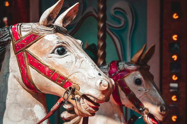 Um cavalo de carrossel com arreio vermelho e padrões decorativos.