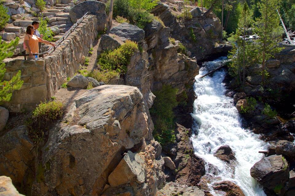 A rocky gorge with a waterfall and a stone bridge.