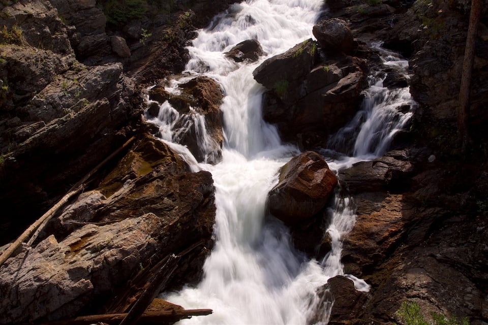 A waterfall cascading over rocks in a forested area.