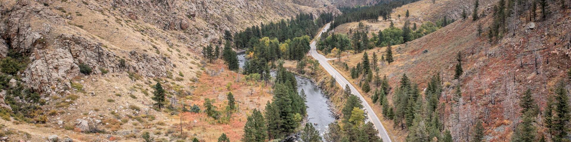 A winding road through a mountainous valley with a river running alongside it.