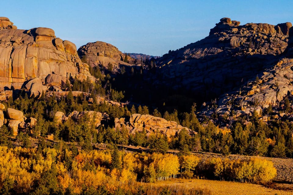 A rugged mountain landscape with large rock formations and dense forest.