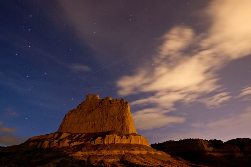 A large rock formation under a starry night sky.