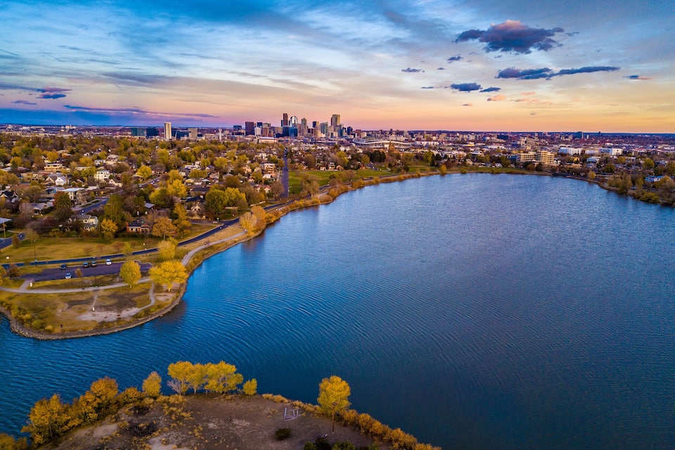 A river winding through a city with autumn foliage, a prominent skyscraper, and a park area.