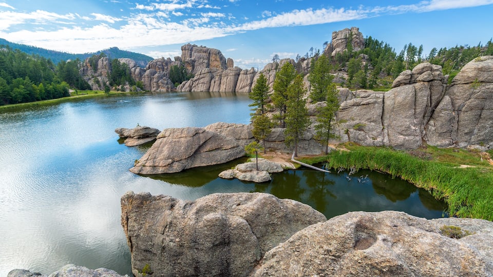 A calm lake surrounded by large boulders and trees.