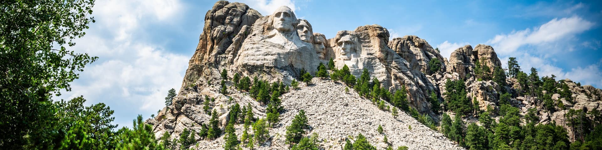 Mount Rushmore National Monument memorial in South Dakota with blue sky and cumulus clouds