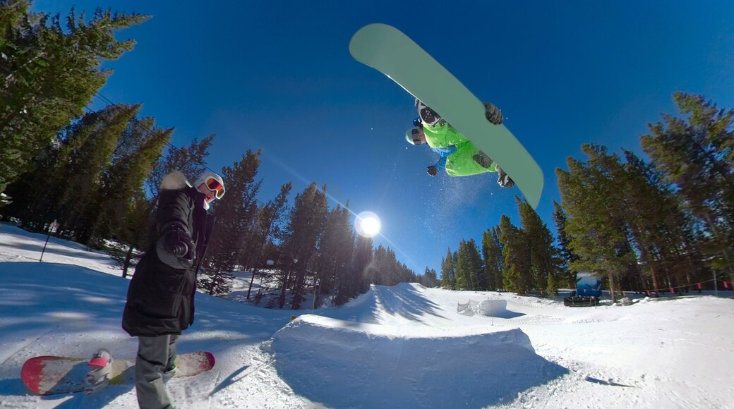 SELFIE: Woman takes a selfie while snowboarder jumps off kicker and does a trick