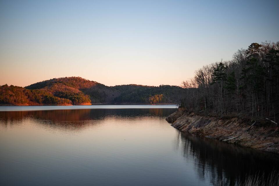 A calm lake with a forested hill in the background.