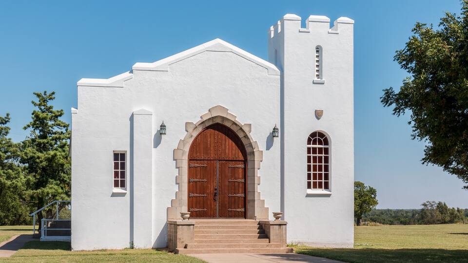 A white church with a large wooden door and a bell tower.