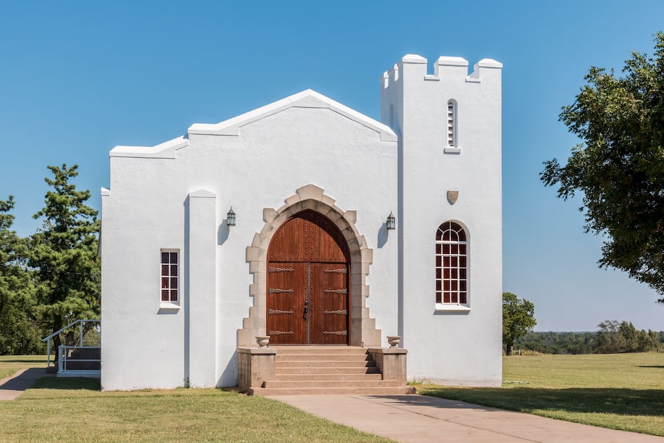 A white church with a large wooden door and a bell tower.