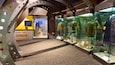 A museum exhibit with military artifacts, including helmets and uniforms, displayed in glass cases.