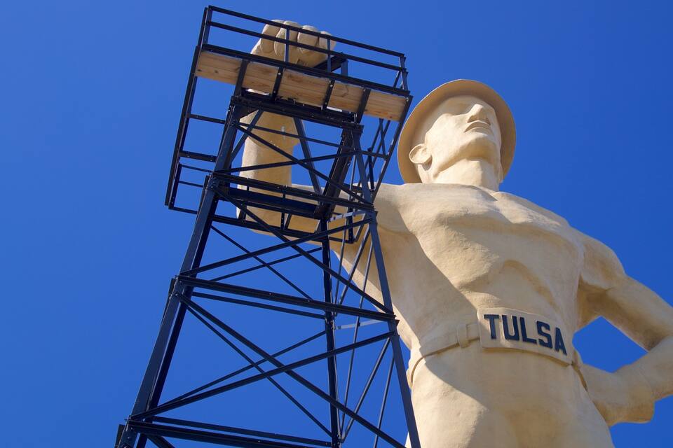 A statue with a sign reading "TULSA" against a clear blue sky.