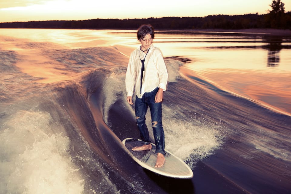 A person surfing on a wave with a sunset in the background.