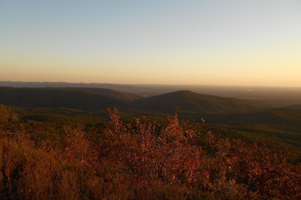 A mountainous landscape with autumn foliage in the foreground and a clear sky in the background.